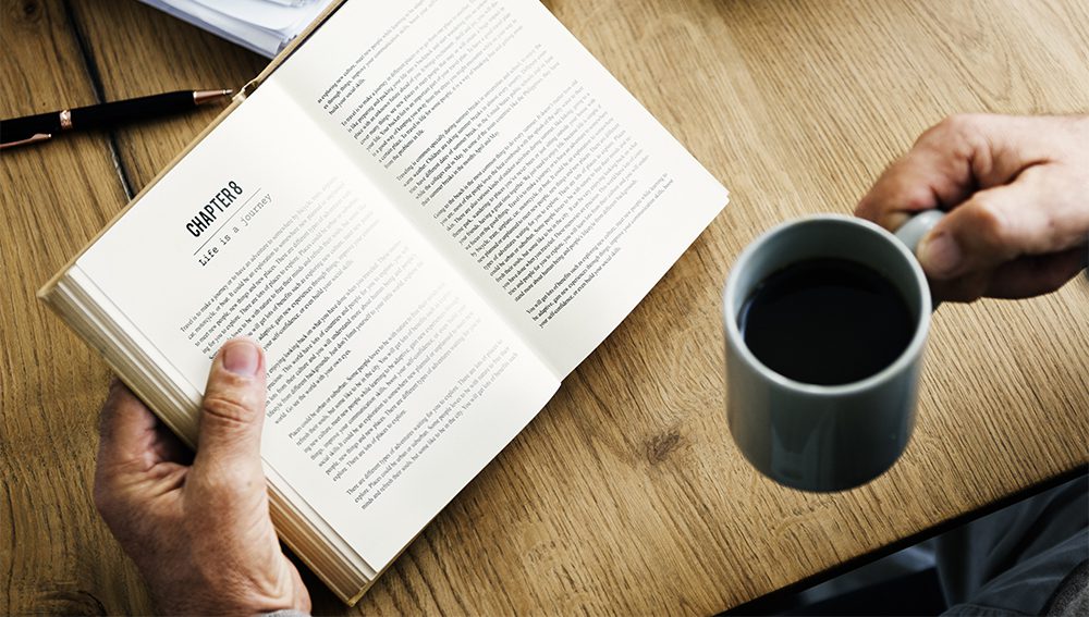 Man reading a book and drinking coffee